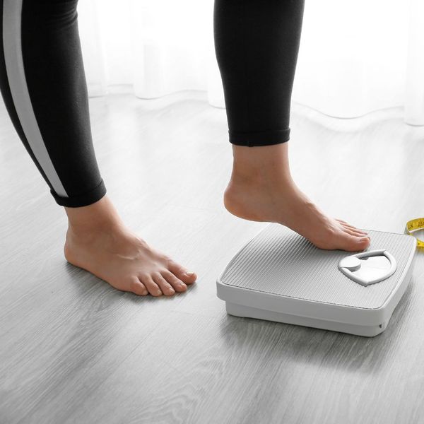 A woman stepping onto a scale at home