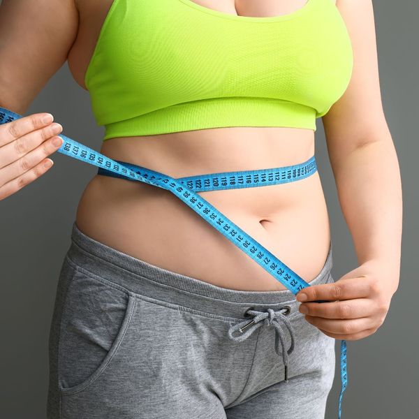 Woman wrapping a tape measure around her belly. 