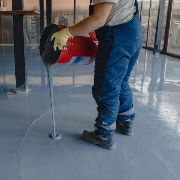 a person pouring epoxy on a floor