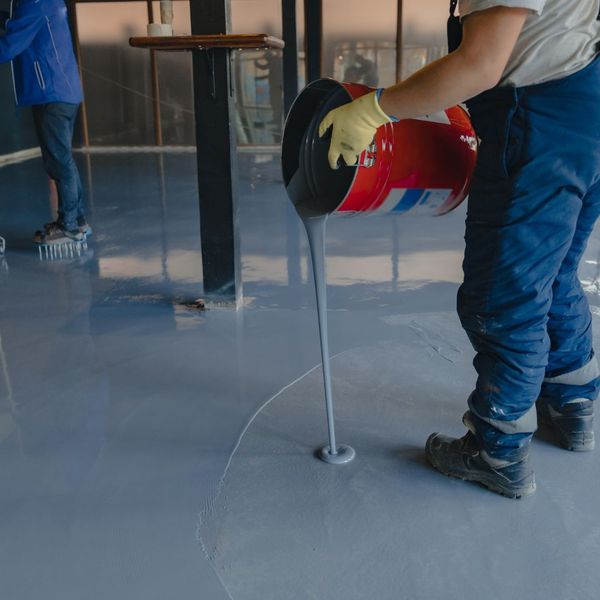 person pouring a coating on a garage floor