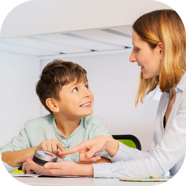 a woman showing a little boy an object and talking to him