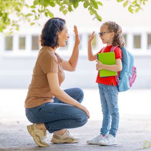 a mom kneeling to her little girls height and giving her a high five
