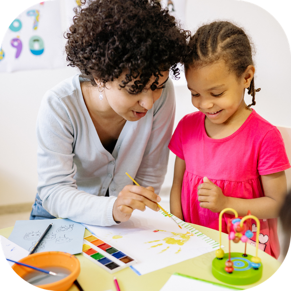 a woman showing a little girl how to paint 