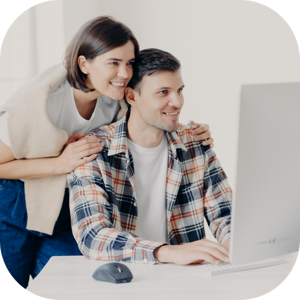 a pair of parents looking at a computer screen together and smiling