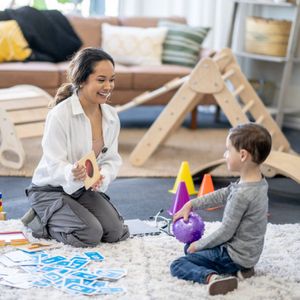 woman sitting on the ground with a child playing with toys