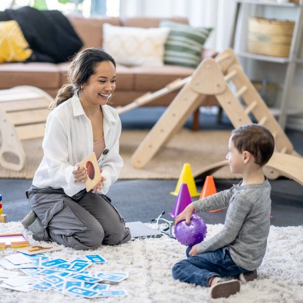 woman sitting on the ground with a child playing with toys