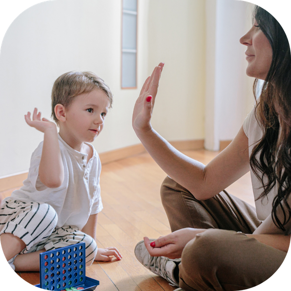 child giving therapist a high-five while playing a game 
