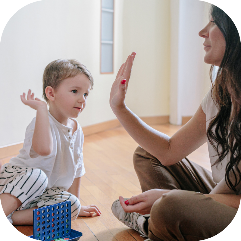 child giving therapist a high-five while playing a game 