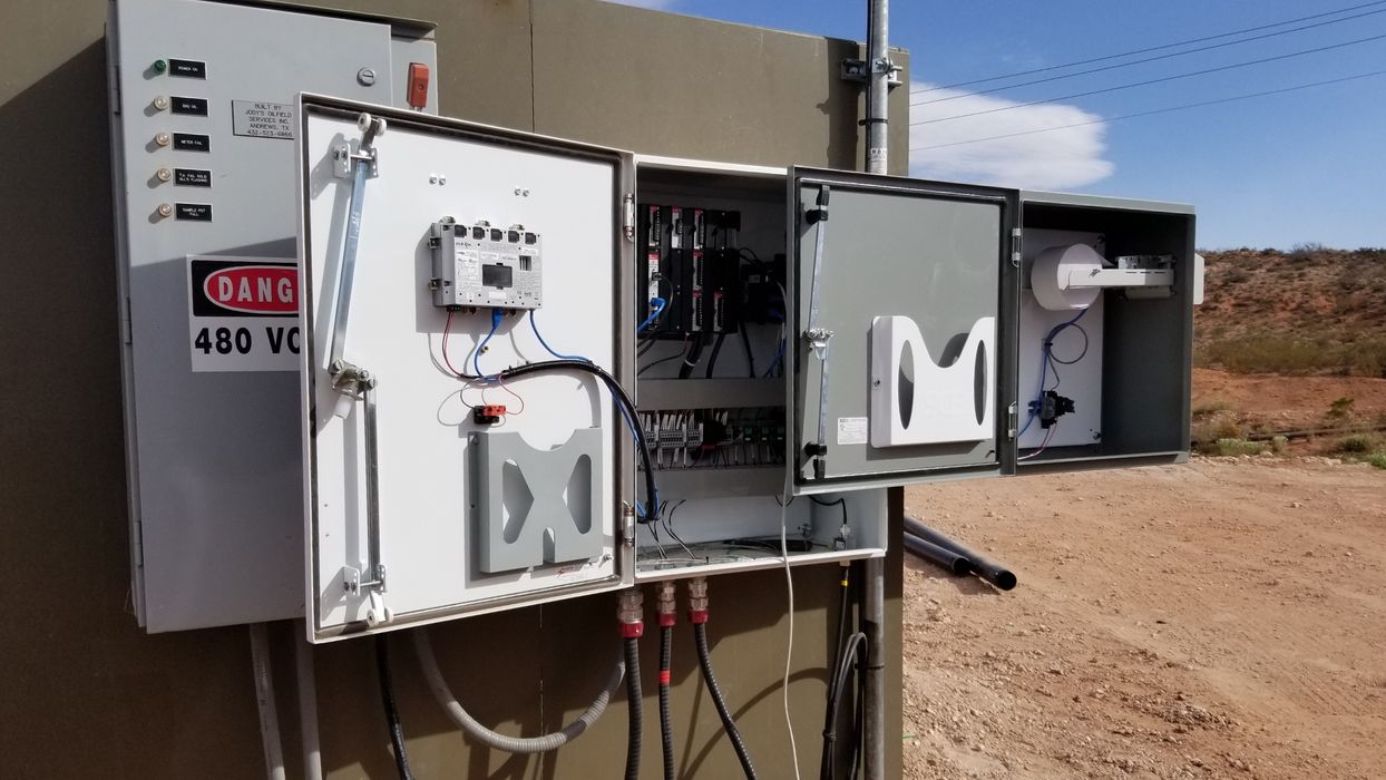 A dynamic wide shot of a modern, well-lit G&C Optimization control panel fabrication workshop, with multiple stages of custom panel builds visible—from empty enclosures to complex wired systems—and skilled technicians working diligently.