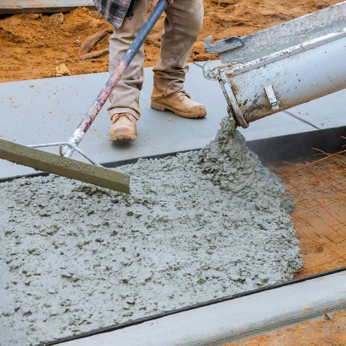 An image of a construction crew pouring concrete for a foundation, with rebar in the foreground.