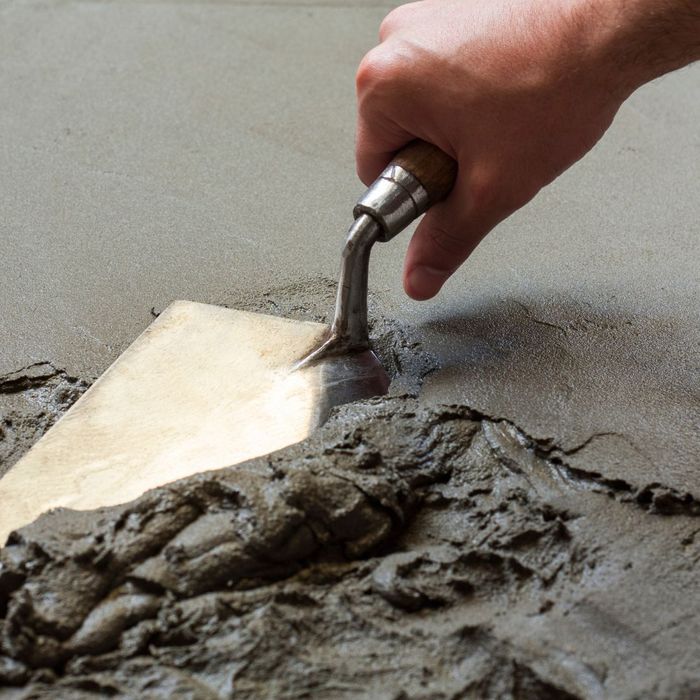 A close-up image of a person's hand using a trowel to smooth out wet concrete, showing craftsmanship. A close-up image of a person's hand using a trowel to smooth out wet concrete, showing craftsmanship.