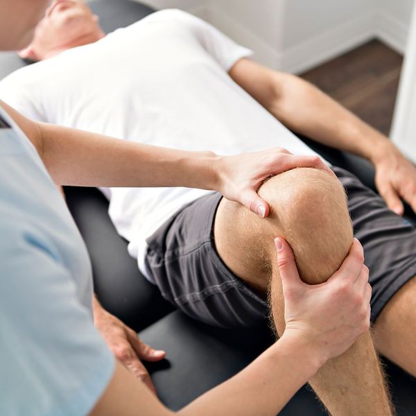 woman testing mans knee mobility in clinic