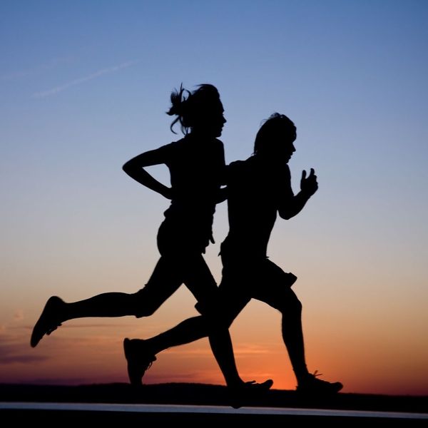 silhouettes of two people running at dusk