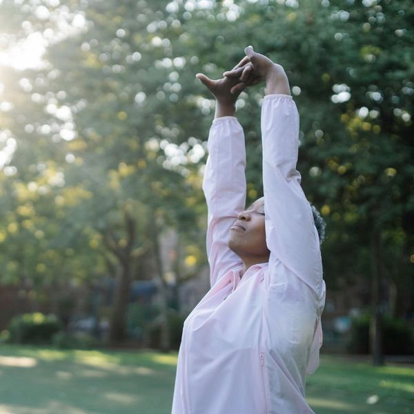 a woman stretching her arms up towards sky