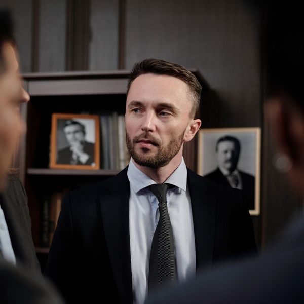 A close-up portrait of a professional security specialist in a suit and tie during a high-level briefing or consultation.