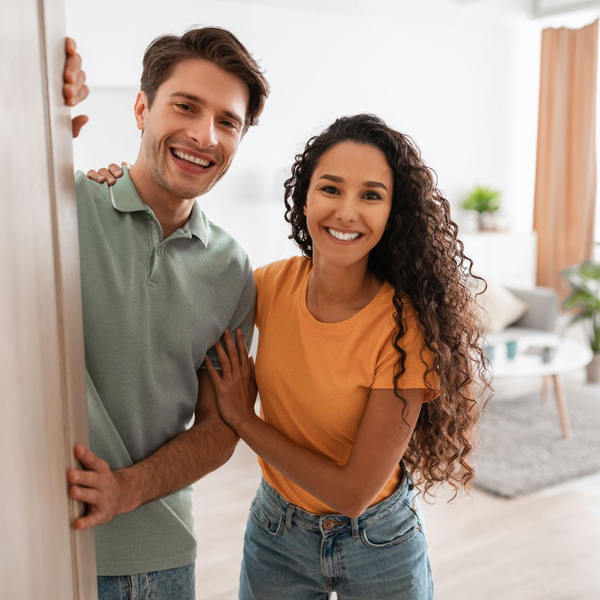 smiling couple opening door to apartment