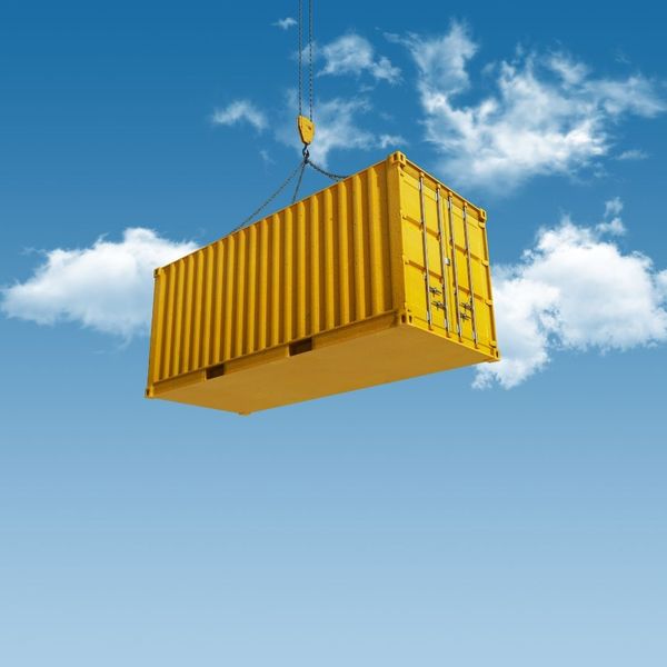 bright yellow container lifted by crane against blue sky
