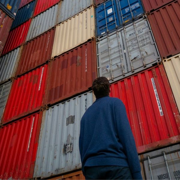 man looking up at tall stack of containers