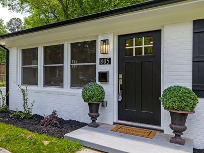 A home with a bright white exterior and a black front door
