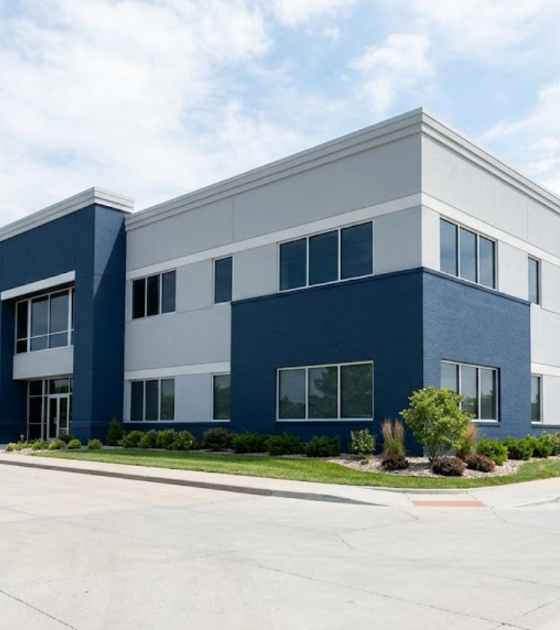 A wide photograph capturing the finished exterior of a newly painted commercial office complex in Omaha, featuring crisp navy blue and light gray walls under a bright sky.