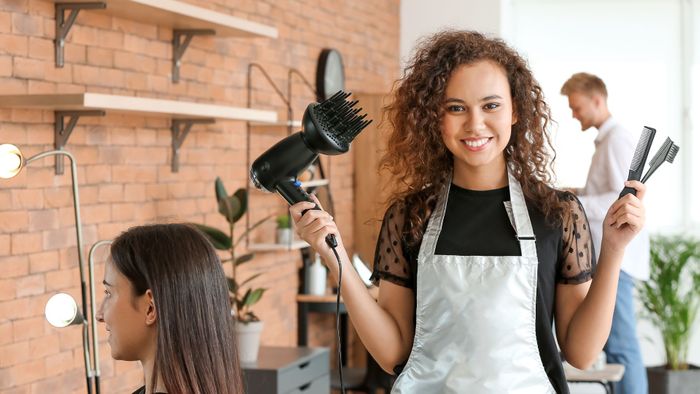 Hair stylist holding diffuser and combs and smiling