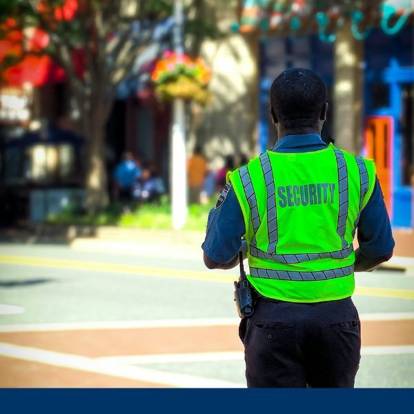 Security officer in reflective vest walking along street