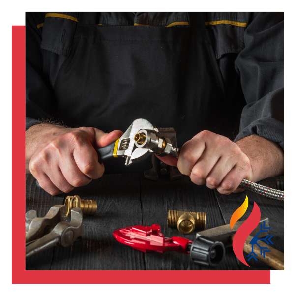 An HVAC tech using a wrench on a valve connected to a hose