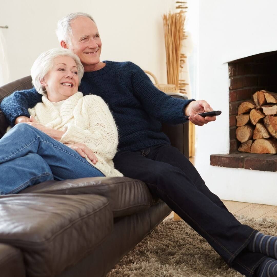 couple sitting on a couch in a warm home couple sitting on a couch in a warm home