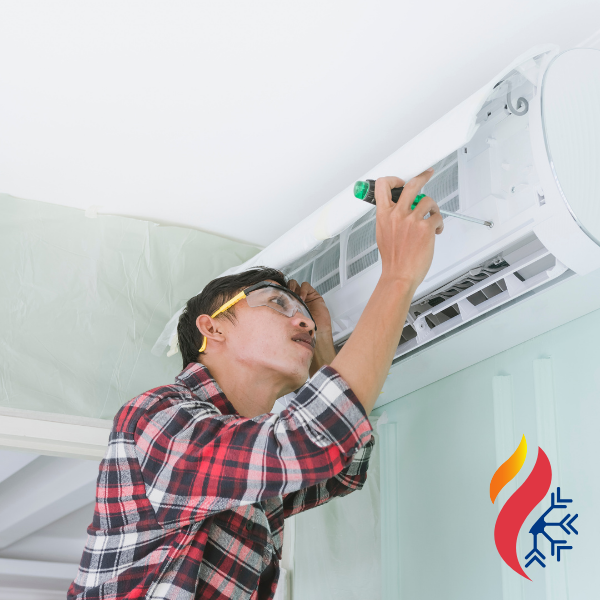 An HVAC tech using a screwdriver under the hood of a mini-split unit