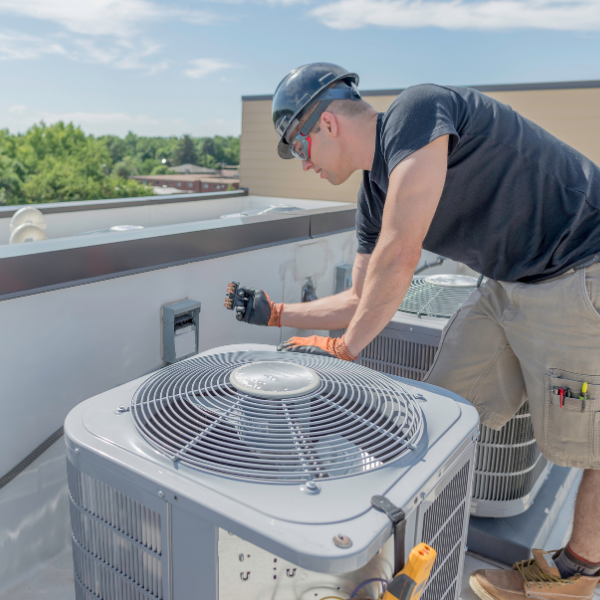 man installing AC unit on roof