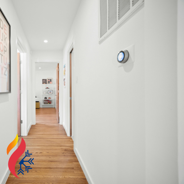 A digital thermostat sitting on the wall of a hallway