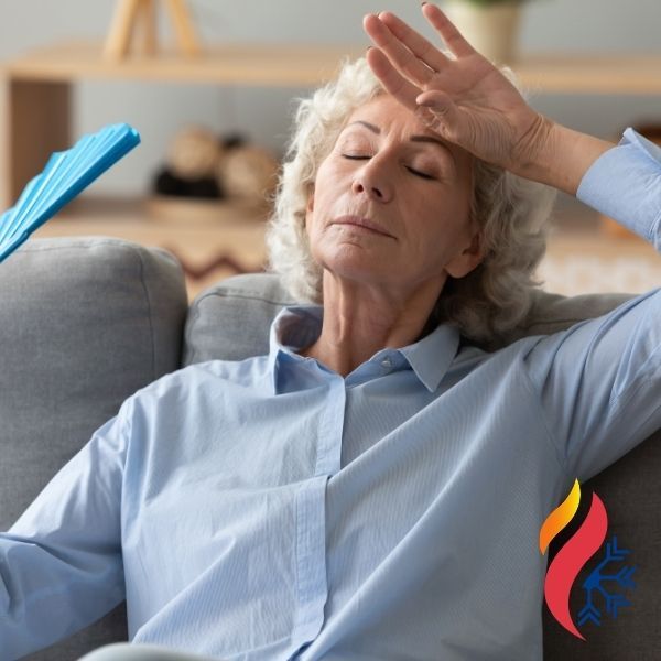 older woman fanning herself off while sitting on a couch