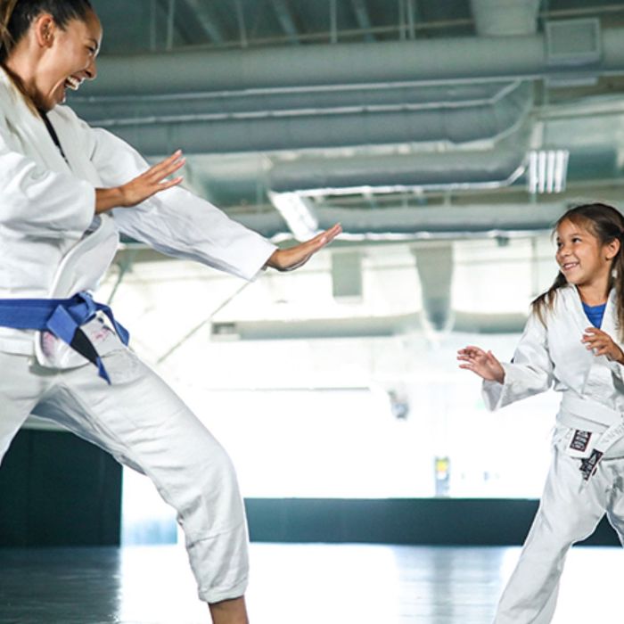 instructor teaching young girl jiu-jitsu