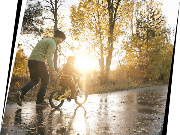 man helping child on bicycle in park