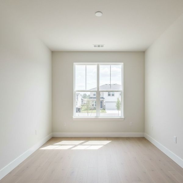Empty, well-lit spare bedroom with a large window Empty, well-lit spare bedroom with a large window