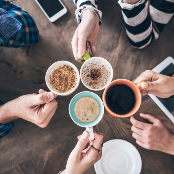 Four people cheering with coffee