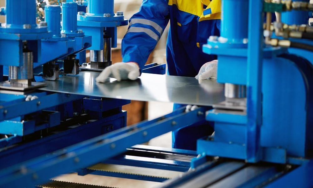 worker carefully using machine to bend/cut sheet metal