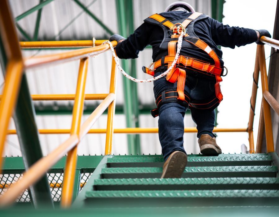 Image of construction worker wearing safety harness and safety line working at high place