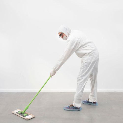 person in hazmat suit cleaning floor