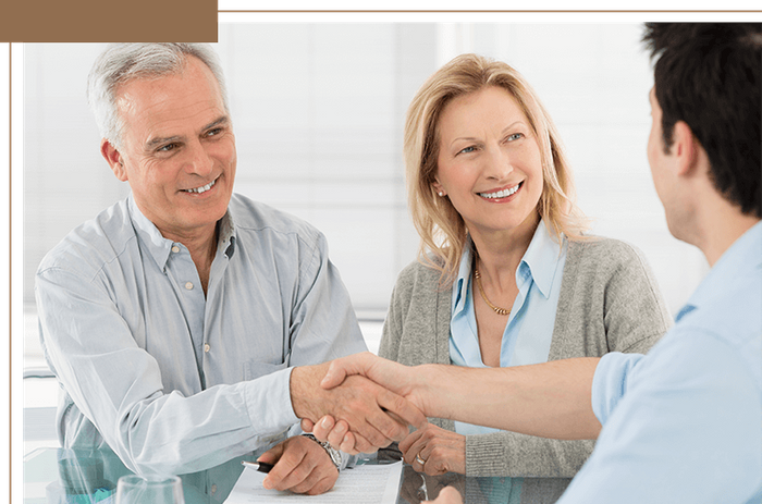 a couple with paperwork in front of them shaking hands with a lawyer