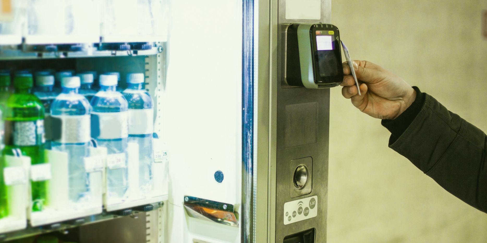 Person using a card to pay at a vending machine