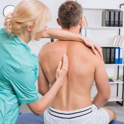 Chiropractor places hand along the spine of a male patient who is sitting up straight