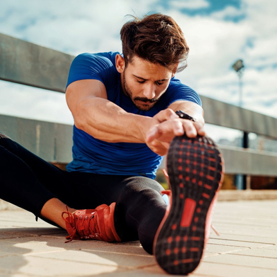 Athletic man sitting on the ground and stretching