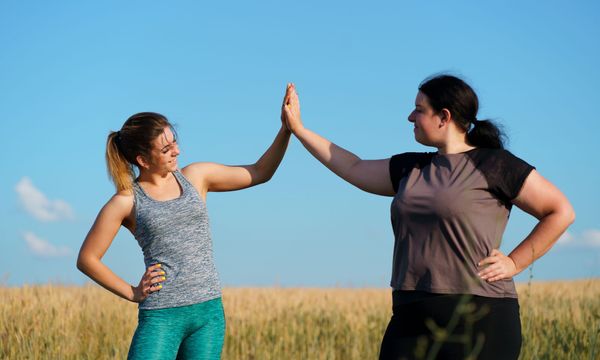 woman outside exercising and high fiving