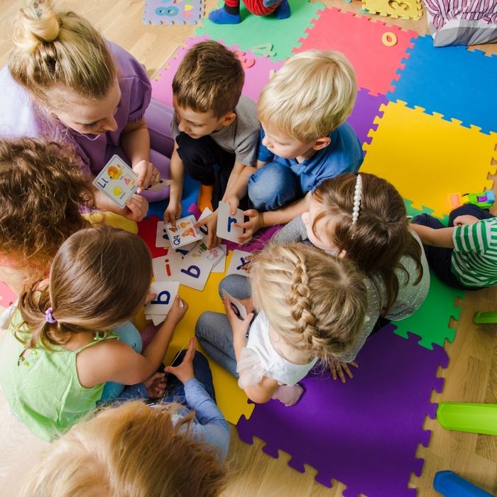 teacher working with students on play mat
