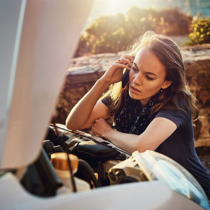 woman looking under a vehicle's hood