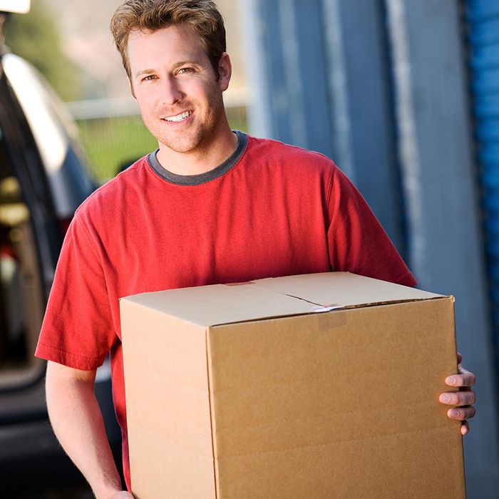 smiling man carrying a box to a storage unit