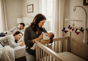 Mother feeding baby with parents in background