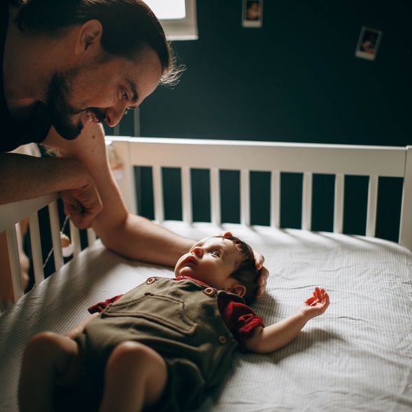 Father putting baby in a crib.