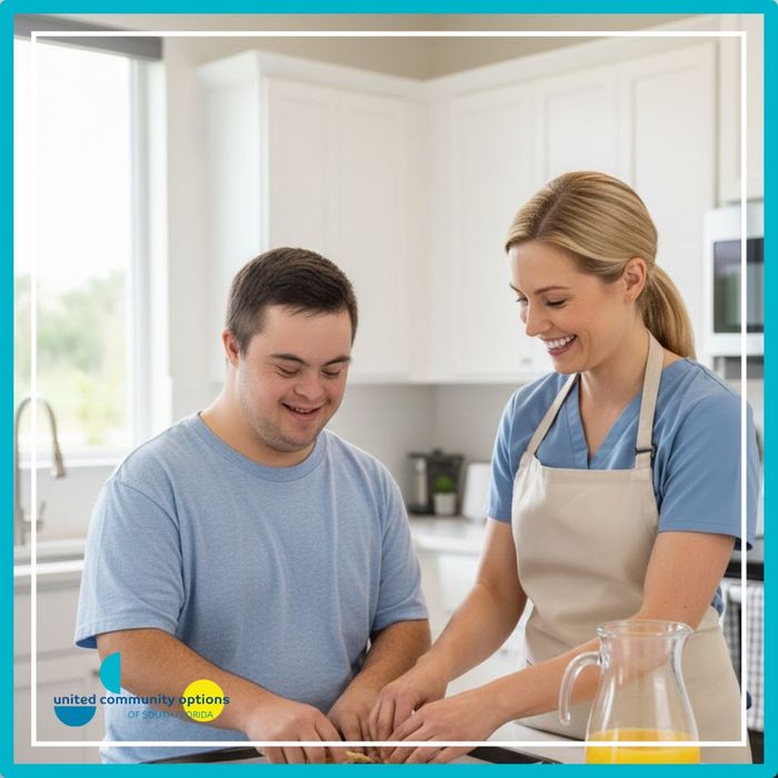 Young man with Down syndrome and a female caregiver baking cookies in a clean, modern kitchen.